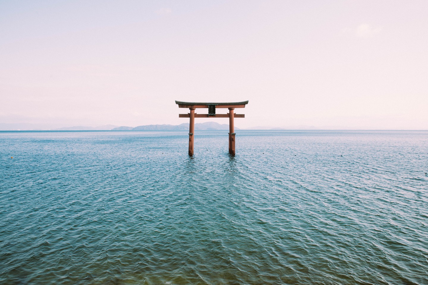 A torii gate standing in calm water